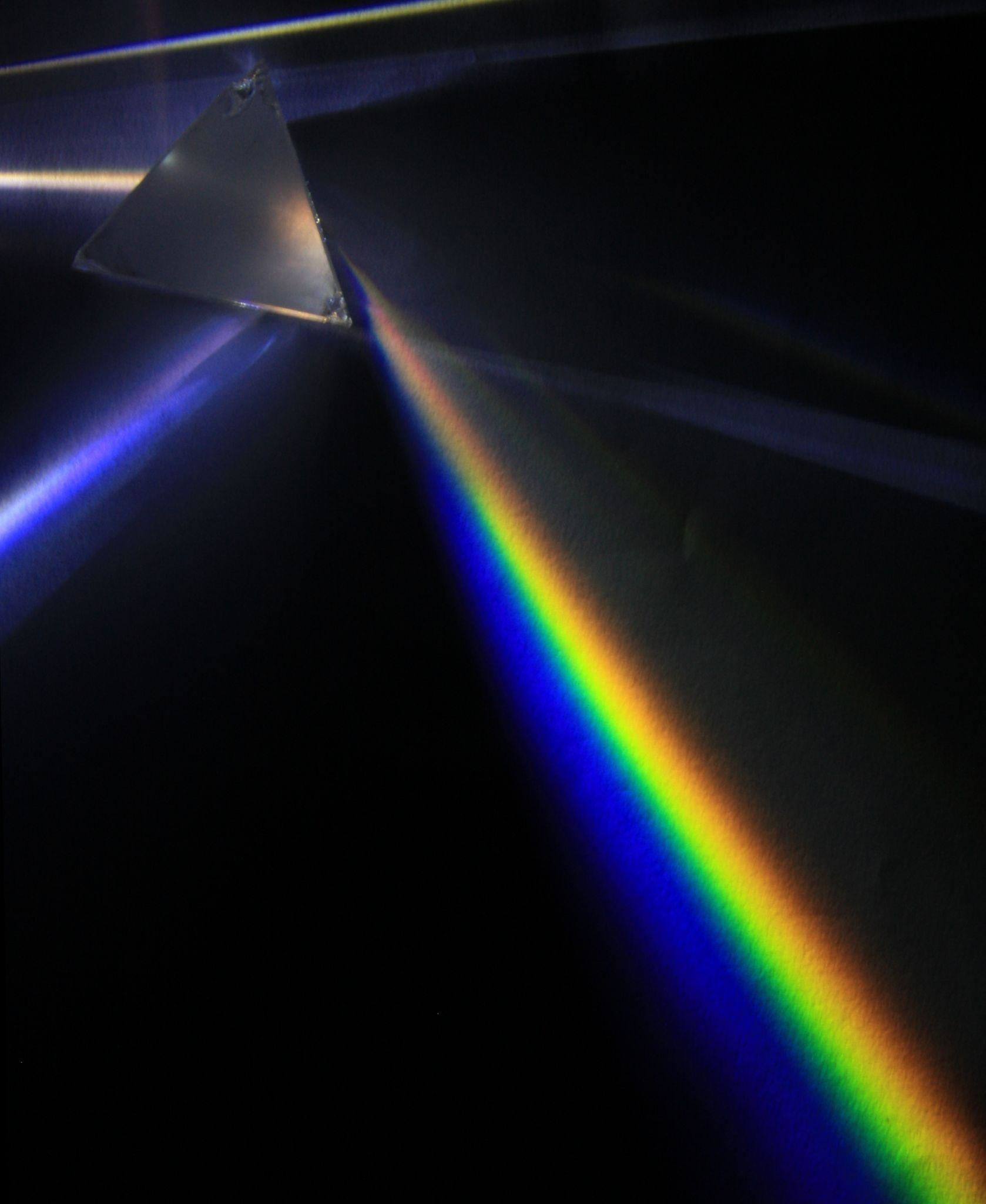 Разложение белого светового луча в цветной спектр при прохождении через стеклянную призму