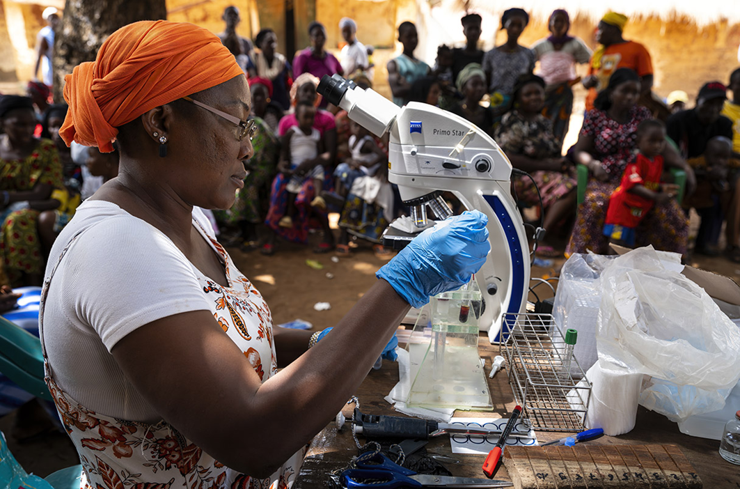 Уму Камара, руководитель диагностического отдела Национальной программы по борьбе с забытыми тропическими болезнями Гвинеи, использует микроскопию для поиска паразитов в крови пациентов с подозрением на сонную болезнь